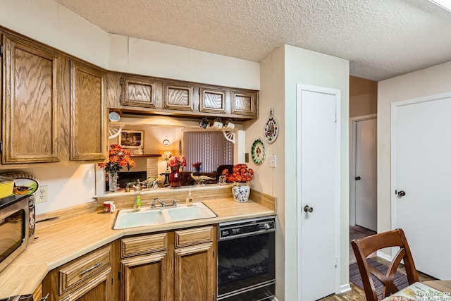 kitchen featuring dishwasher, a textured ceiling, and sink