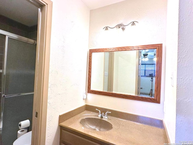 bathroom featuring vanity, an enclosed shower, and toilet