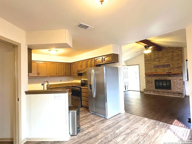 kitchen featuring kitchen peninsula, wood-type flooring, lofted ceiling with beams, and appliances with stainless steel finishes