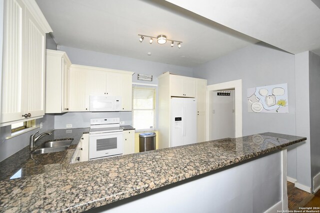 kitchen with white appliances, dark wood-type flooring, dark stone counters, sink, and kitchen peninsula