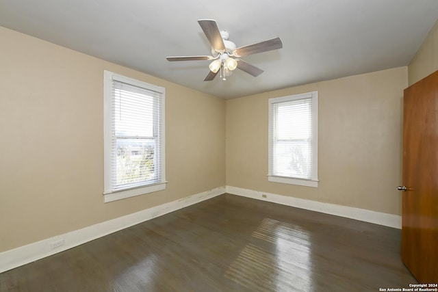 spare room with dark wood-type flooring, ceiling fan, and a healthy amount of sunlight