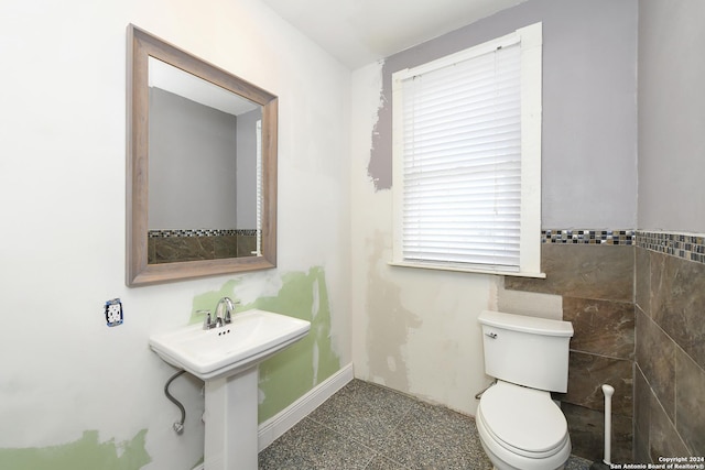 bathroom with sink, a healthy amount of sunlight, tile walls, and toilet