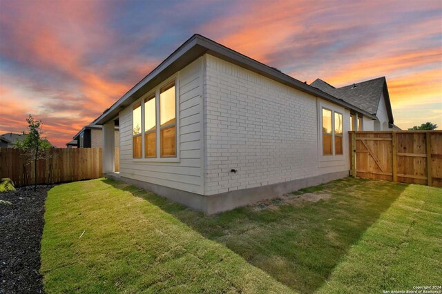 property exterior at dusk featuring a lawn