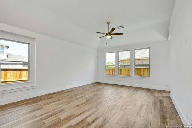 empty room with ceiling fan, vaulted ceiling, and light hardwood / wood-style floors