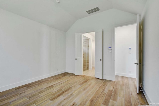 unfurnished bedroom with light hardwood / wood-style floors and vaulted ceiling