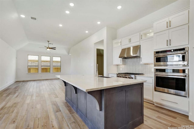 kitchen featuring stainless steel appliances, white cabinetry, light hardwood / wood-style floors, and range hood