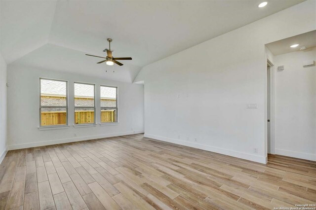 spare room with light wood-type flooring, vaulted ceiling, and ceiling fan