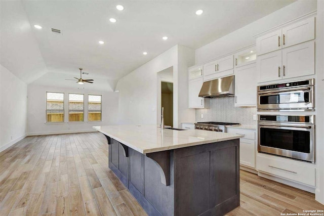 kitchen featuring white cabinets, light hardwood / wood-style floors, stainless steel appliances, and extractor fan