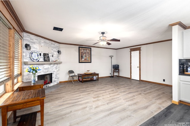 living area featuring ceiling fan, light hardwood / wood-style floors, crown molding, and a fireplace