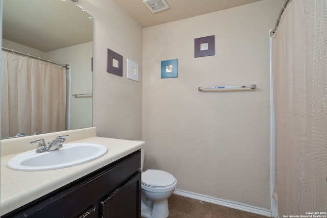 bathroom featuring tile patterned flooring, a textured ceiling, vanity, and toilet