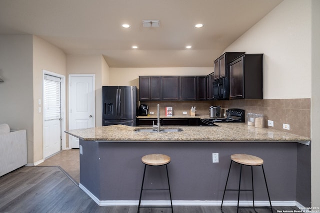 kitchen featuring a breakfast bar, sink, light hardwood / wood-style flooring, appliances with stainless steel finishes, and kitchen peninsula