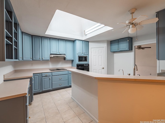 kitchen with blue cabinetry, a skylight, kitchen peninsula, light tile patterned flooring, and black appliances