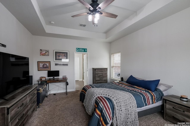 carpeted bedroom featuring a raised ceiling and ceiling fan