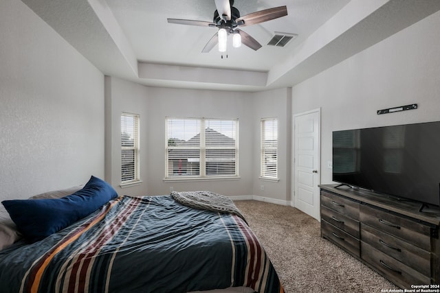 bedroom with carpet flooring, ceiling fan, and a tray ceiling