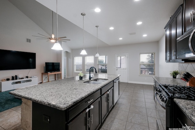 kitchen featuring light stone countertops, appliances with stainless steel finishes, sink, light tile patterned floors, and a center island with sink