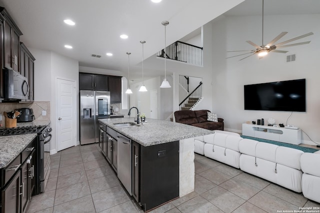 kitchen featuring appliances with stainless steel finishes, tasteful backsplash, sink, pendant lighting, and a center island with sink