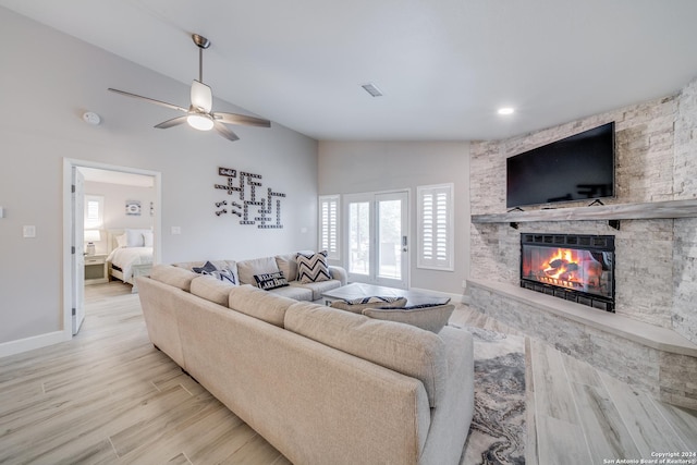 living room featuring a fireplace, light hardwood / wood-style flooring, vaulted ceiling, and ceiling fan