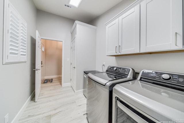 laundry area with cabinets, washer and dryer, and light wood-type flooring