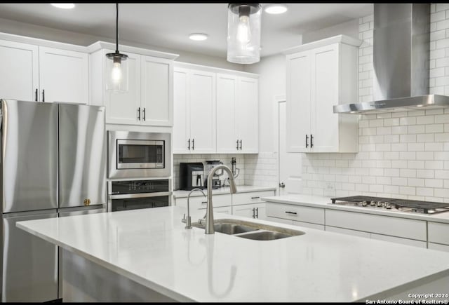 kitchen featuring sink, hanging light fixtures, wall chimney exhaust hood, white cabinetry, and stainless steel appliances