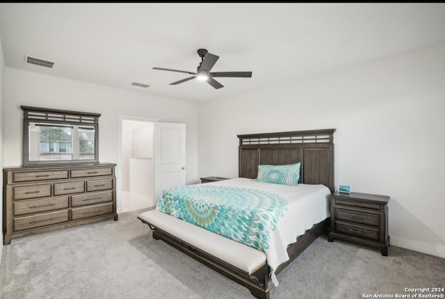 carpeted bedroom with ensuite bath and ceiling fan