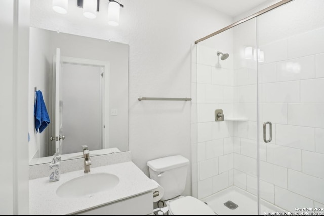 bathroom featuring a shower with door, vanity, and toilet