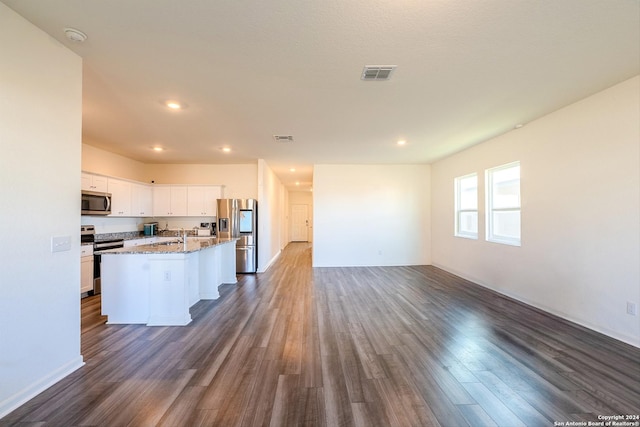 kitchen with white cabinets, stainless steel appliances, dark wood-type flooring, and an island with sink