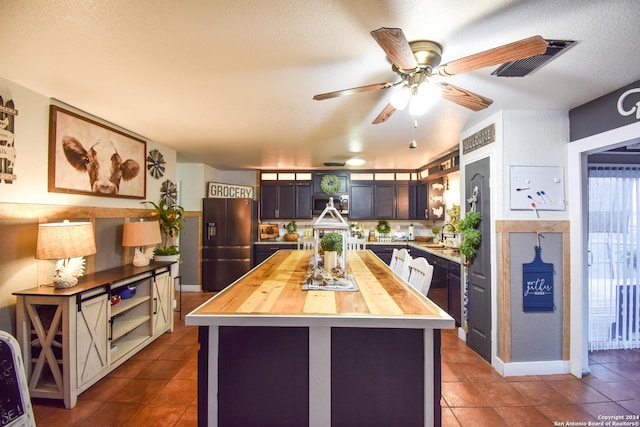 kitchen featuring butcher block countertops, black fridge, a kitchen island, and a textured ceiling