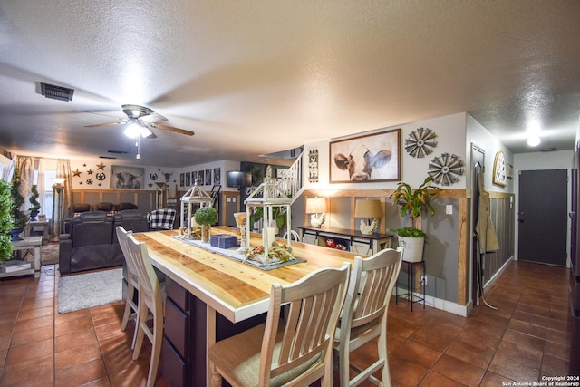 dining area featuring ceiling fan, dark tile patterned flooring, and a textured ceiling