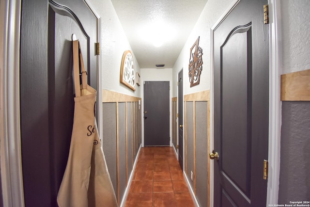 corridor with a textured ceiling and dark tile patterned flooring