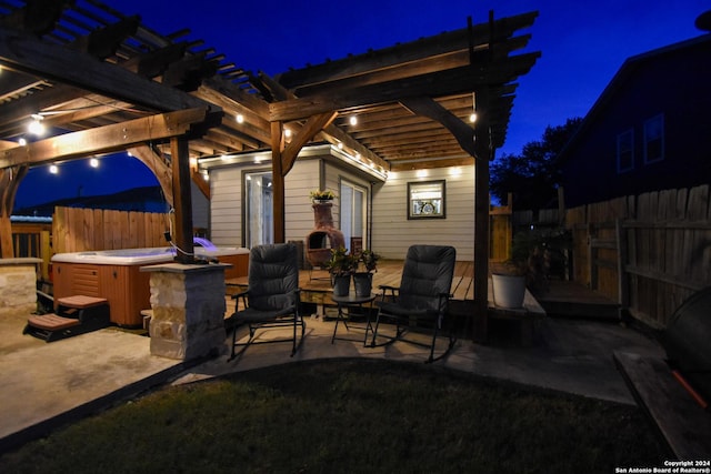 patio at night with a pergola and a hot tub