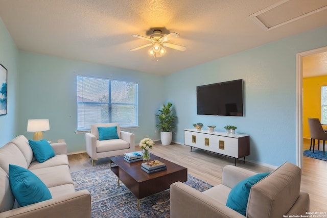 living room with a textured ceiling, light hardwood / wood-style flooring, and ceiling fan