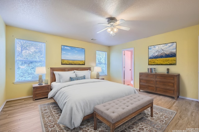 bedroom with ceiling fan, light hardwood / wood-style flooring, and multiple windows