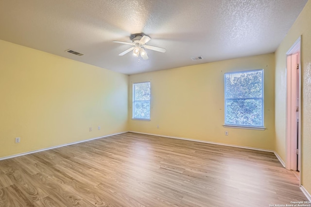 empty room with ceiling fan, light wood-type flooring, and a textured ceiling