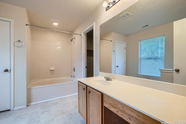 bathroom featuring vanity, a textured ceiling, and tiled shower / bath