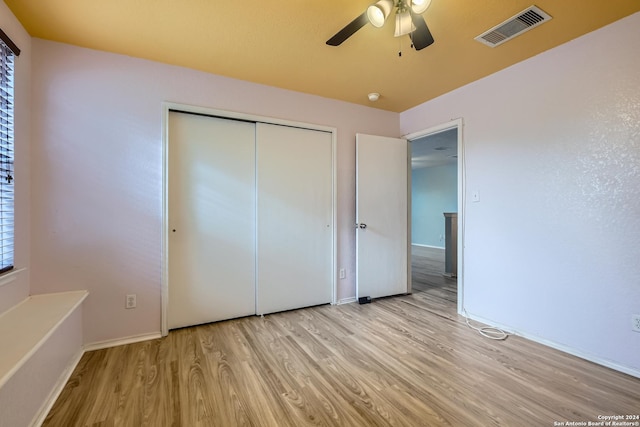 unfurnished bedroom with light wood-type flooring, a closet, and ceiling fan