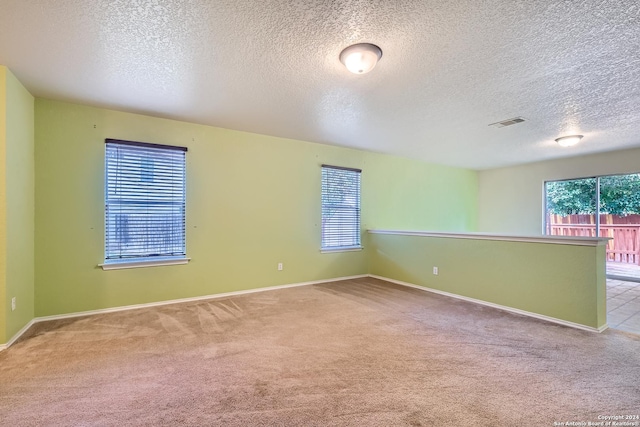 carpeted spare room featuring a textured ceiling