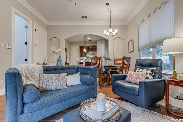 living room with a chandelier, wood-type flooring, and crown molding