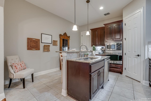 kitchen with dark brown cabinetry, sink, pendant lighting, a kitchen island with sink, and appliances with stainless steel finishes