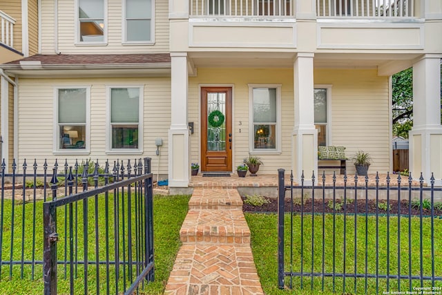 property entrance featuring a lawn and a balcony