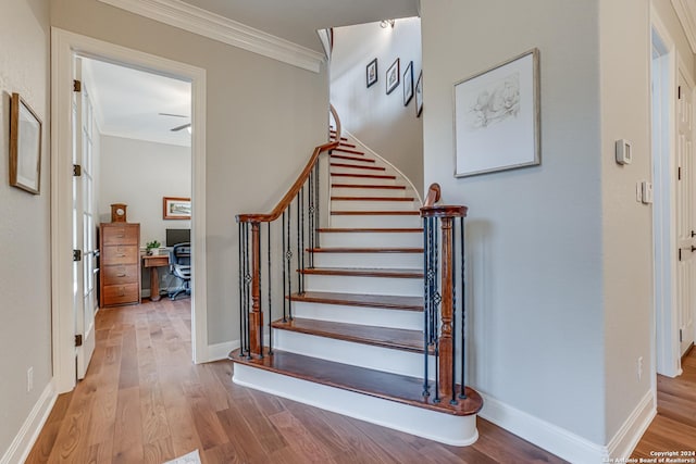 stairway with wood-type flooring and ornamental molding