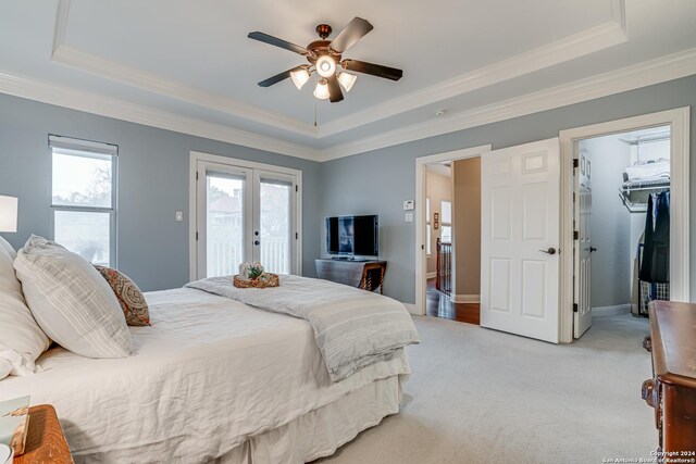 bedroom featuring light carpet, access to outside, a raised ceiling, ceiling fan, and a spacious closet