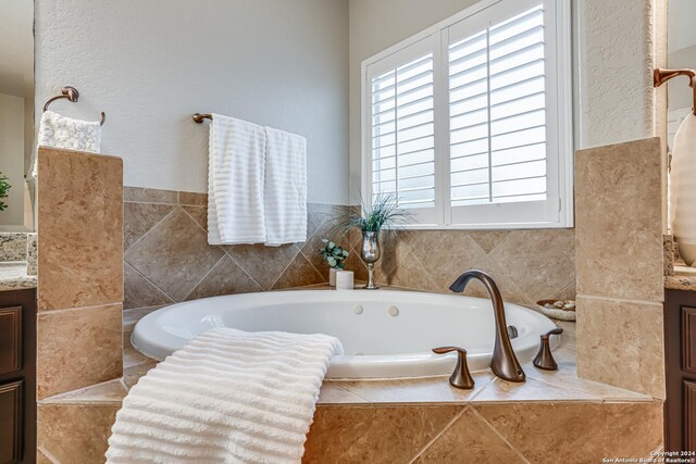 bathroom featuring vanity and a relaxing tiled tub