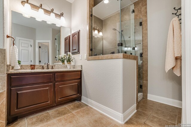 bathroom featuring a tile shower, tile patterned flooring, and vanity