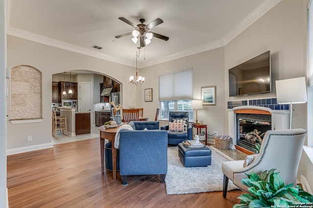 living room with crown molding, light hardwood / wood-style floors, and ceiling fan with notable chandelier