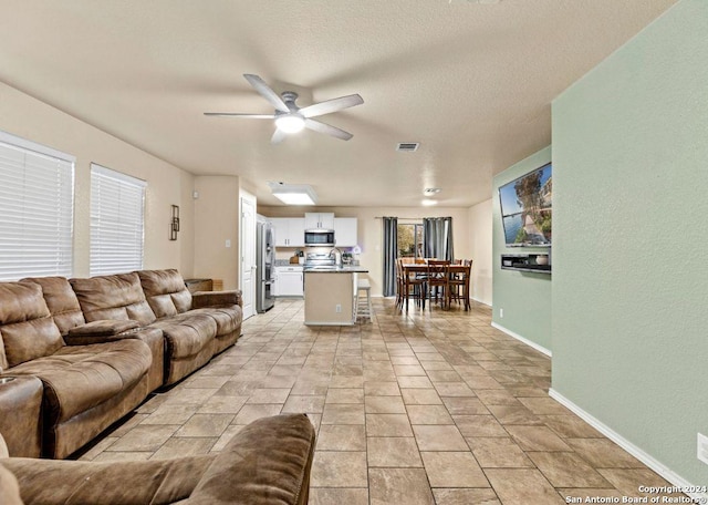 living room featuring ceiling fan and a textured ceiling