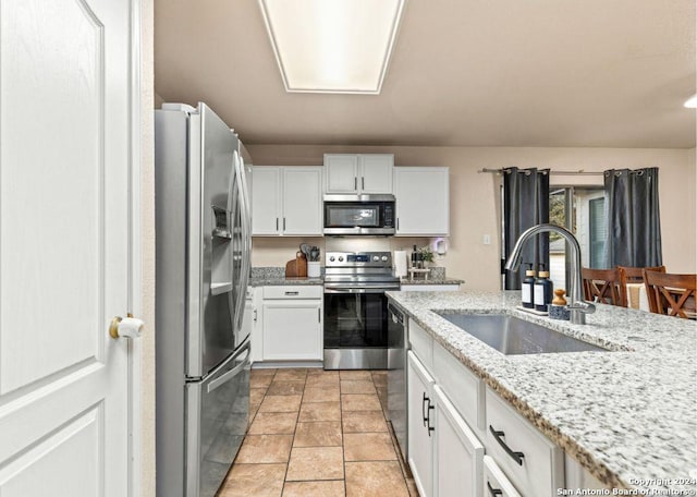 kitchen featuring white cabinetry, sink, stainless steel appliances, and light stone counters