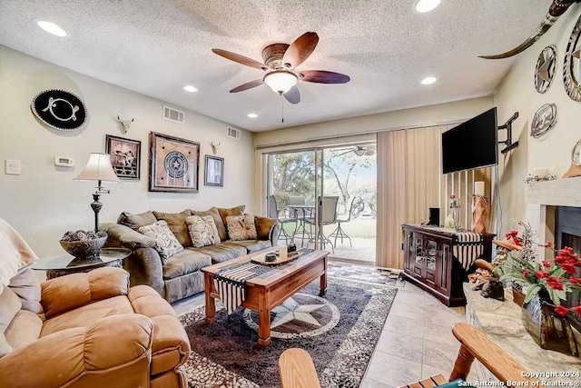 living room with ceiling fan, light tile patterned floors, and a textured ceiling