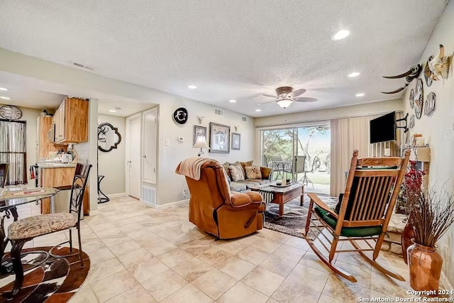 living room featuring ceiling fan and a textured ceiling