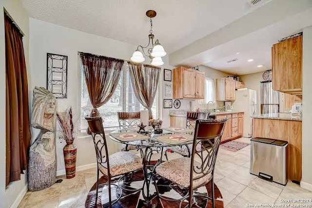 dining room with light tile patterned floors, a textured ceiling, an inviting chandelier, and sink