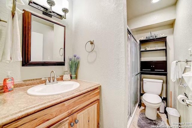 bathroom featuring tile patterned flooring, vanity, toilet, and a shower with shower door